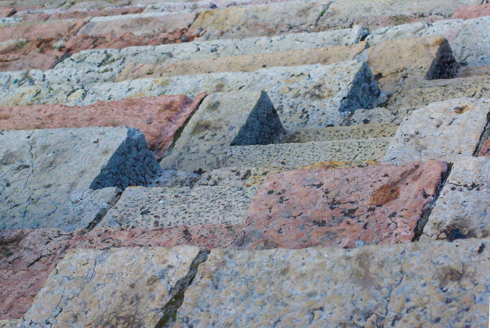 Angular lines of ancient steps steps and rows of seating. Natural sunlight on the colorful stones shows off texture