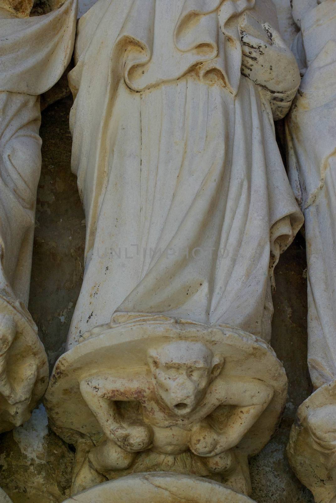 Fourteenth century  marble sculpture of a monkey at the feet of a Catholic apostle at Sé Cathedral, Évora, Portugal