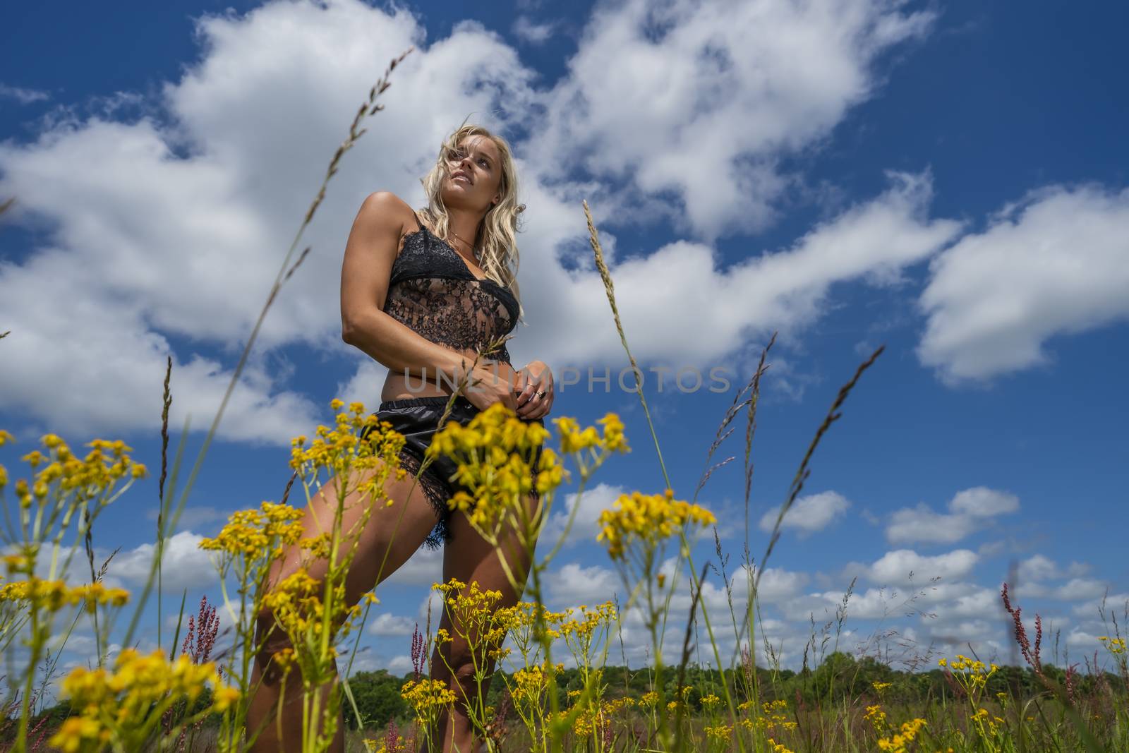 A gorgeous blonde model poses in lingerie in an outdoor environment