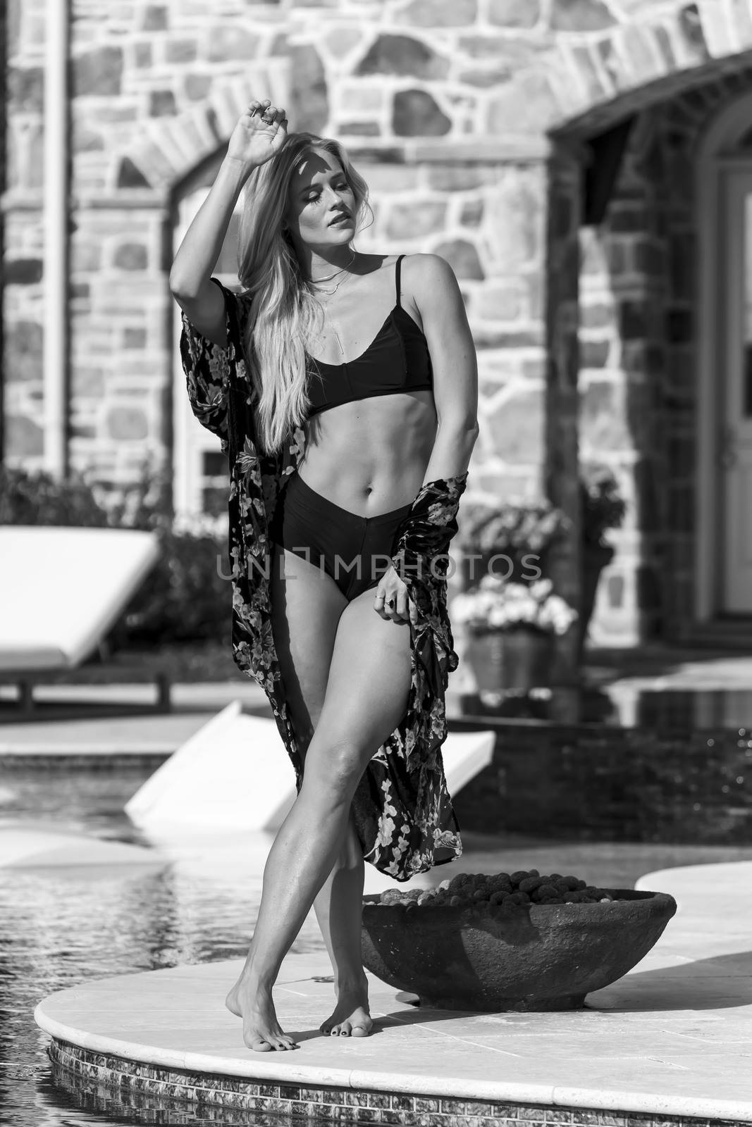 A gorgeous blonde bikini model enjoys a summers day by the pool