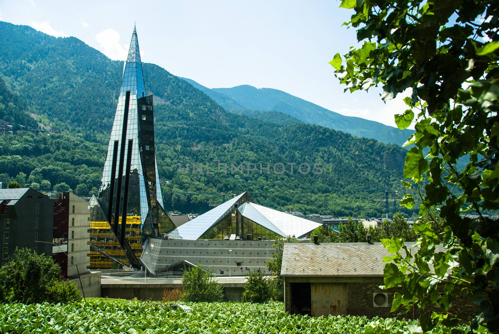 Caldea Spa glass building in Andorra with mountains at the background and tobacco fields at the foreground