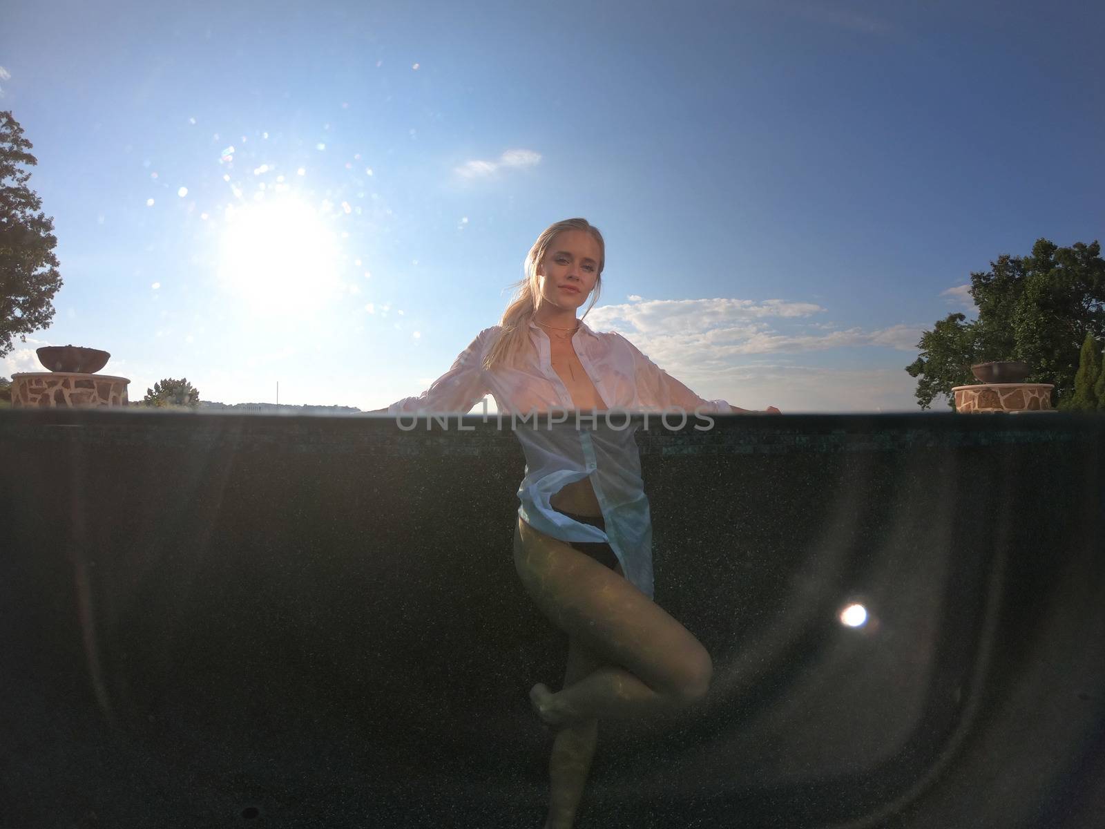 A gorgeous blonde bikini model enjoys a summers day by the pool