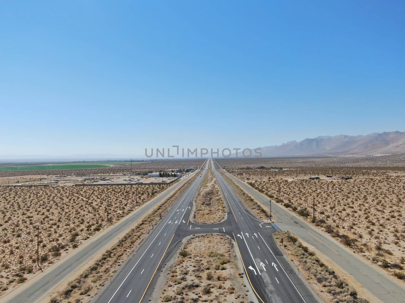 Aerial view of road in the middle of the desert under blue sky in California's Mojave desert, near Ridgecrest.  by Bonandbon