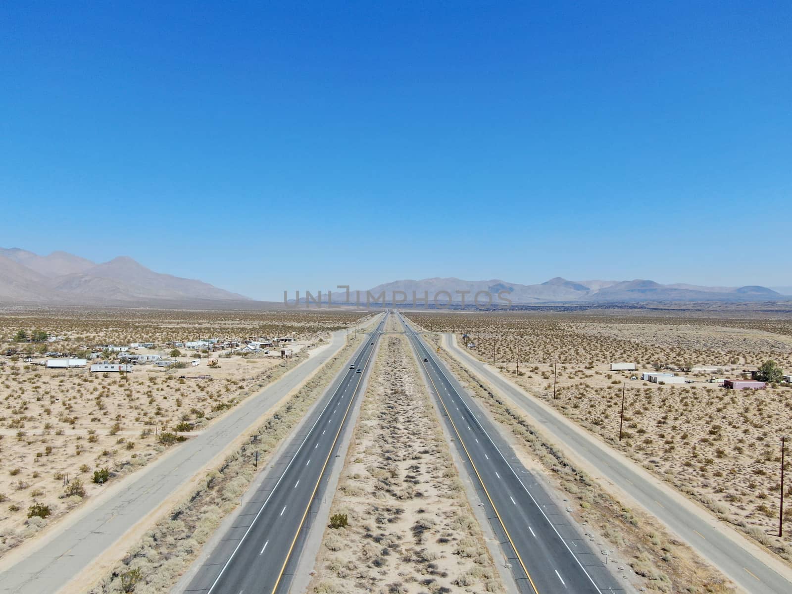 Aerial view of road in the middle of the desert under blue sky in California's Mojave desert, near Ridgecrest.  by Bonandbon