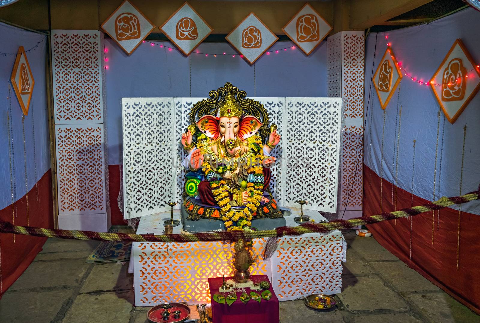 Garlanded deity idol of Lord Ganesha installed with background decorations for festival, in Pune, india.