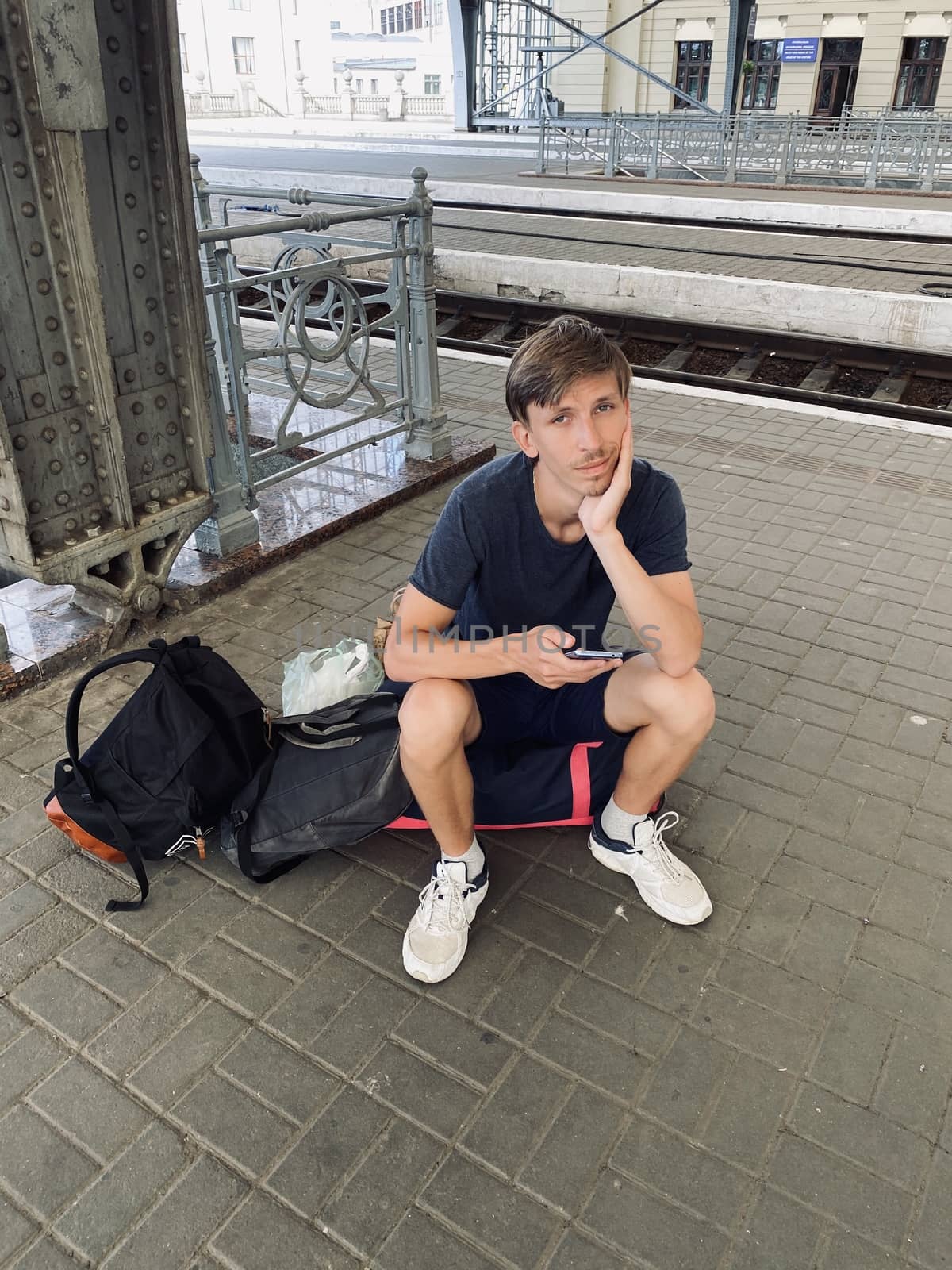 young man sitting on the bag on the railway station