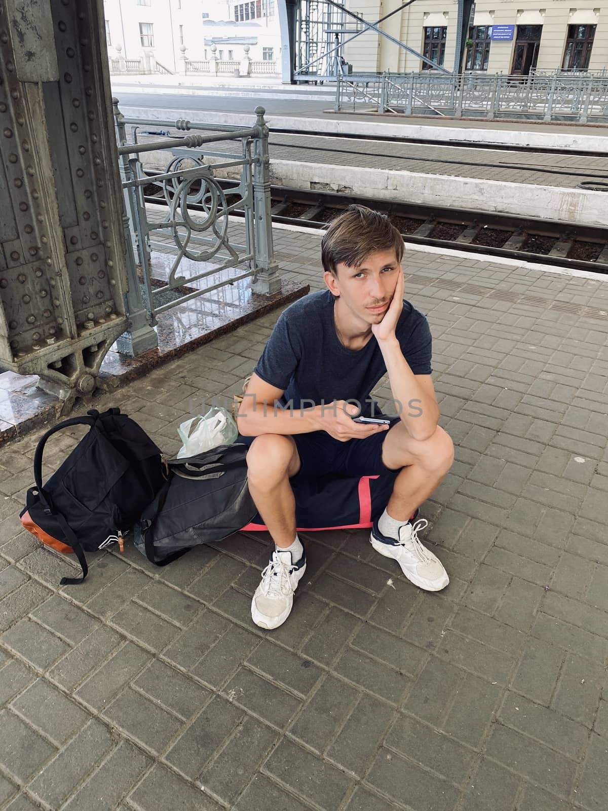 young man sitting on the bag on the railway station