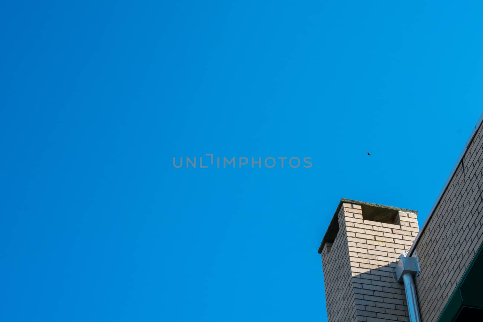 The Chimney of a Building on a Clear Blue Sky by bju12290