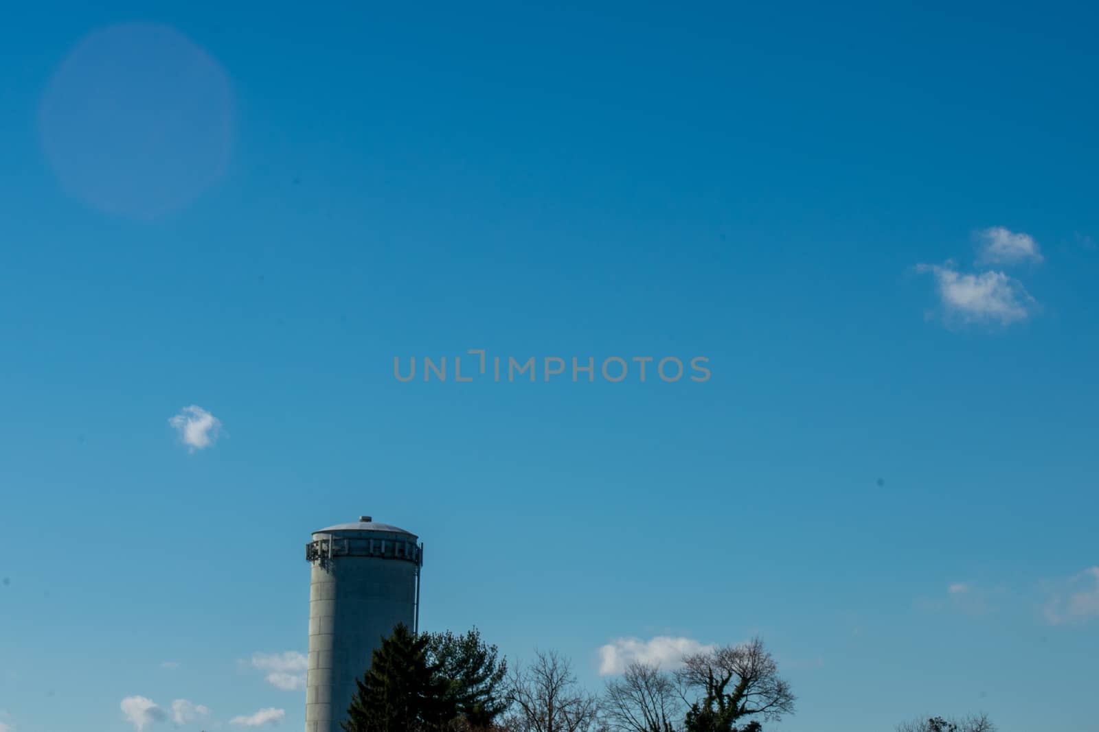 A Large Watertower in the Bottom of the Frame on a Clear Blue Sky