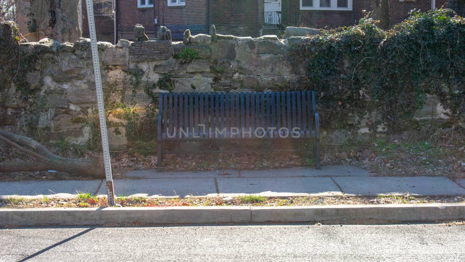 A Park Bench in Front of a Cobblestone Wall in a Suburban Neighborhood