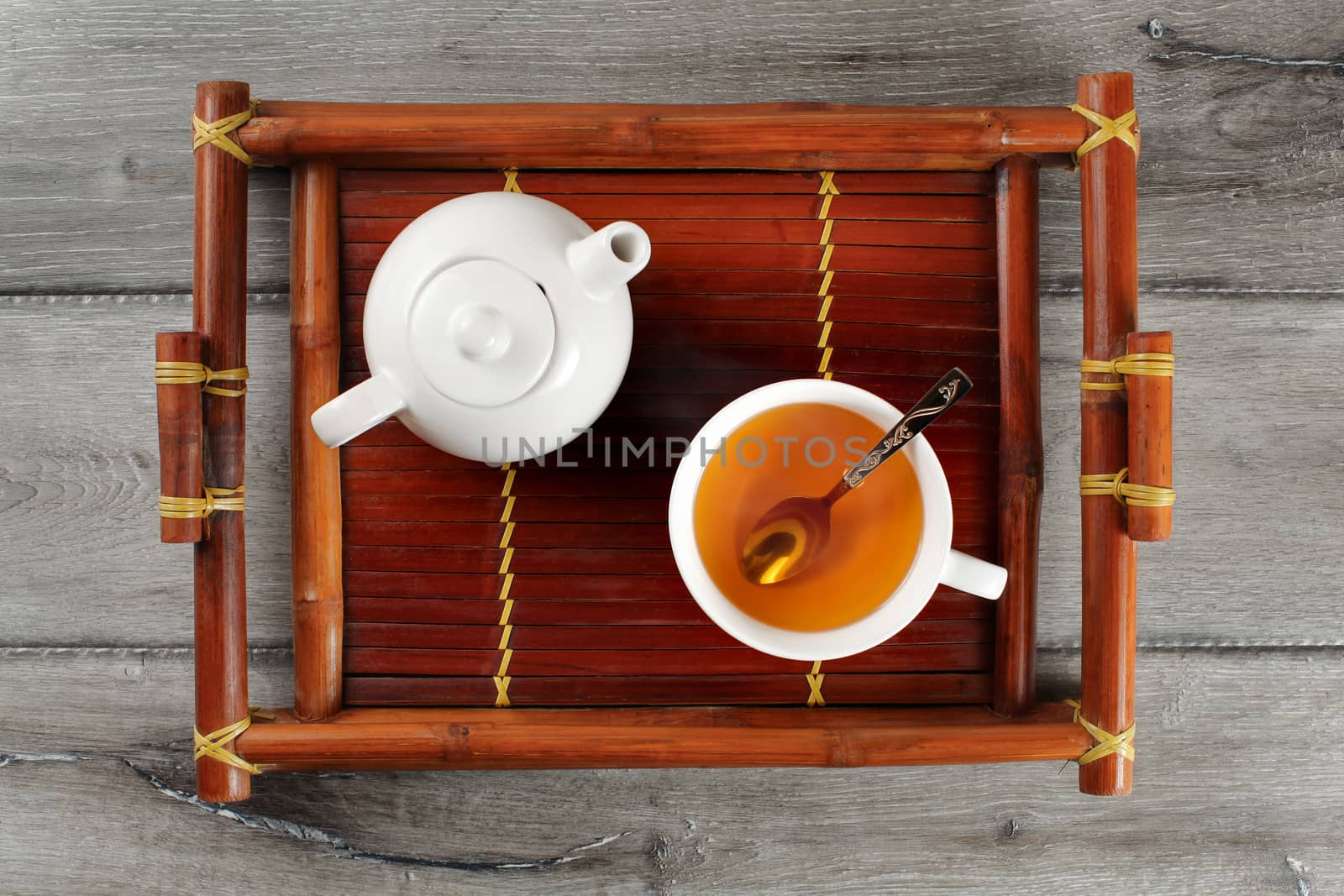 Table top view on bamboo wood tray with small ceramic teapot and by Ivanko