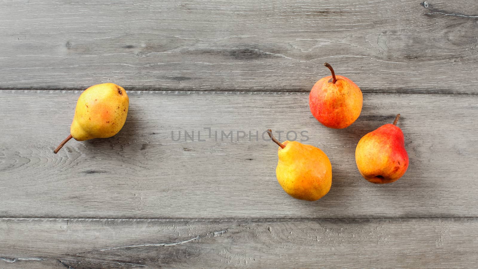 Table top view on four ripe pears placed on gray wood desk. by Ivanko