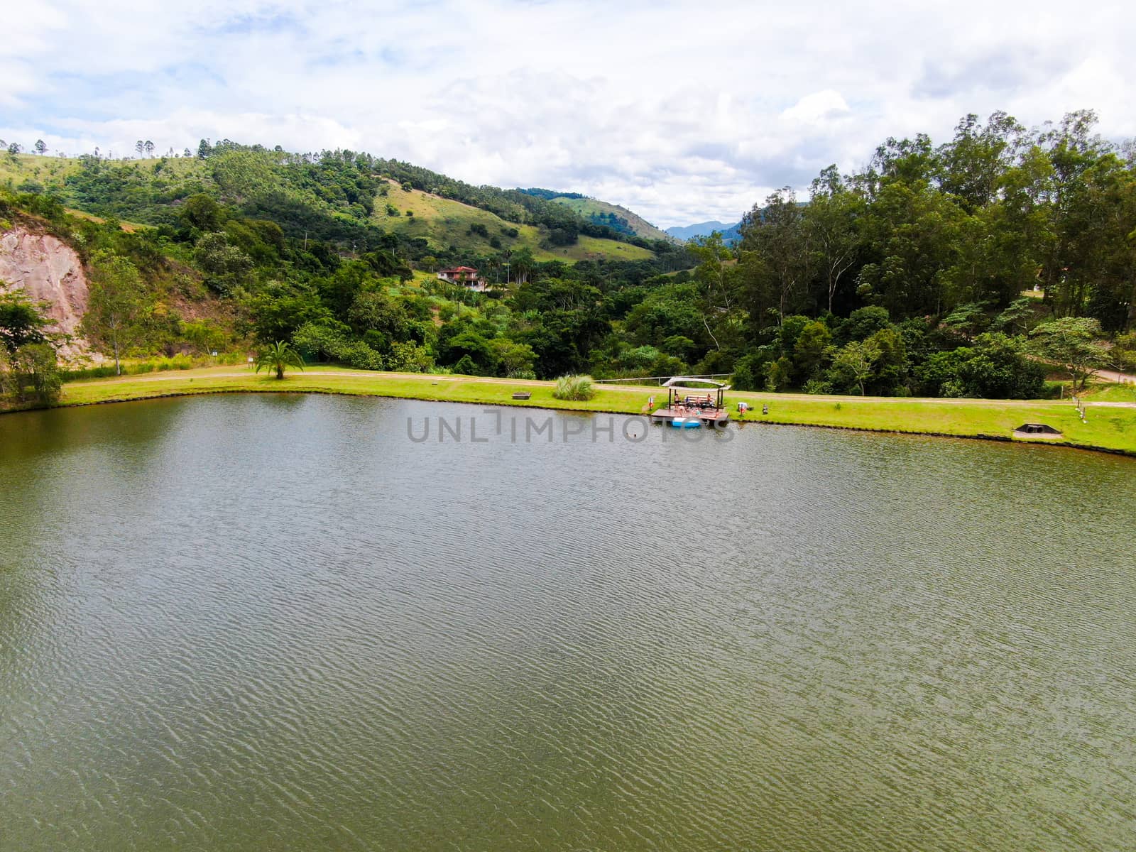 Aerial view of little wood cabana next the lake in the valley, with family enjoying relax moment, swimming and fishing. Monte Alegre Do Sul, Brazil. 