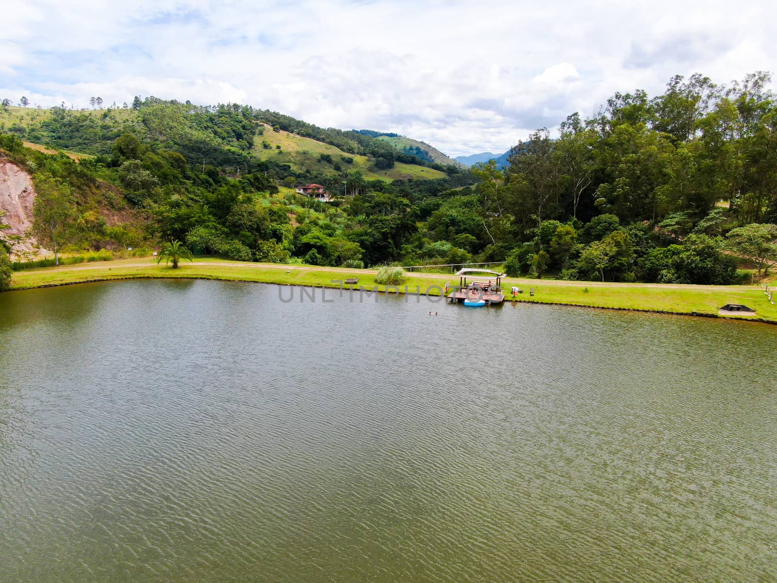 Aerial view of little wood cabana next the lake in the valley, with family enjoying relax moment, swimming and fishing. Monte Alegre Do Sul, Brazil. 