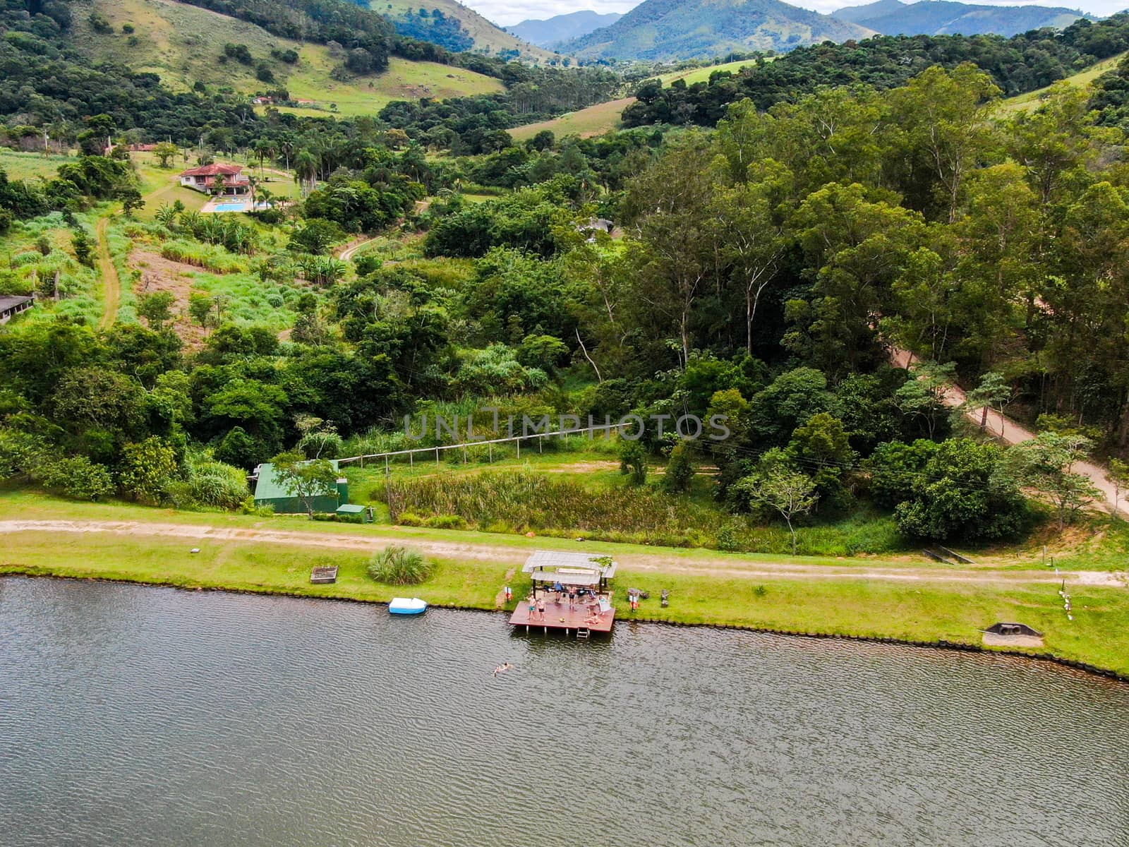 Aerial view of little wood cabana next the lake in the valley, with family enjoying relax moment, swimming and fishing. Monte Alegre Do Sul, Brazil. 