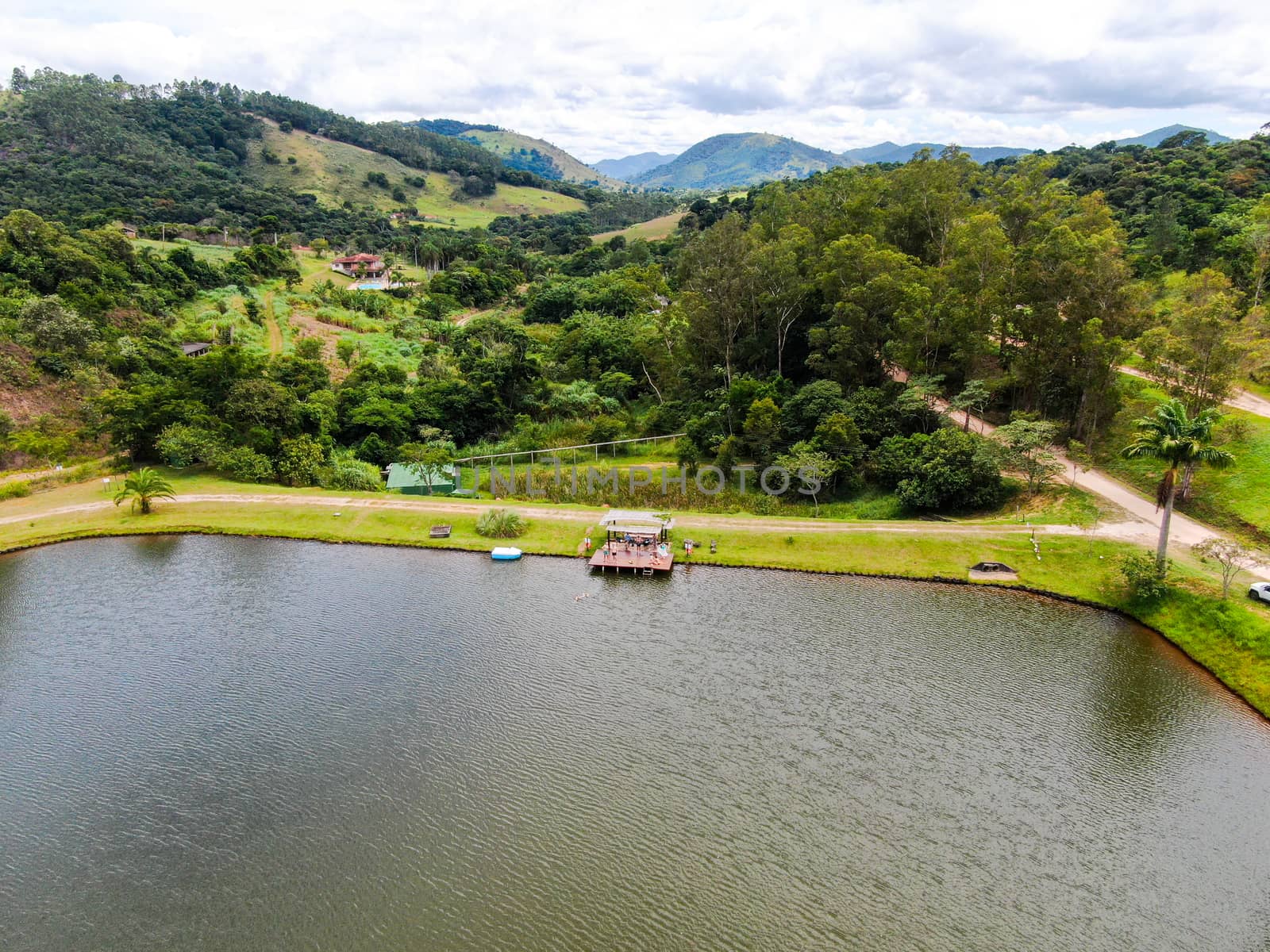 Aerial view of little wood cabana next the lake in the valley, with family enjoying relax moment, swimming and fishing. Monte Alegre Do Sul, Brazil. 