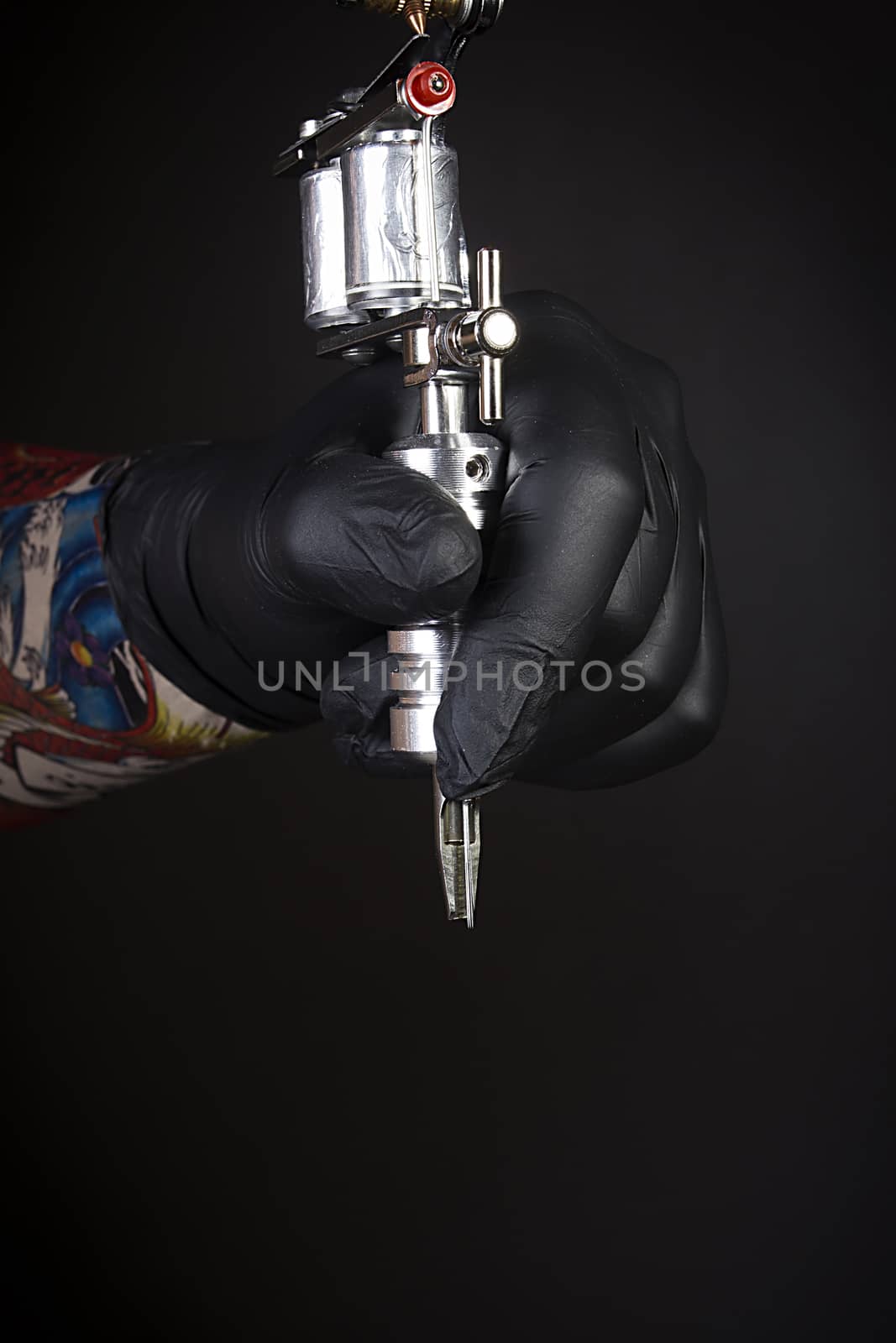 Tattoo machine in artist’s hand isolated on black background