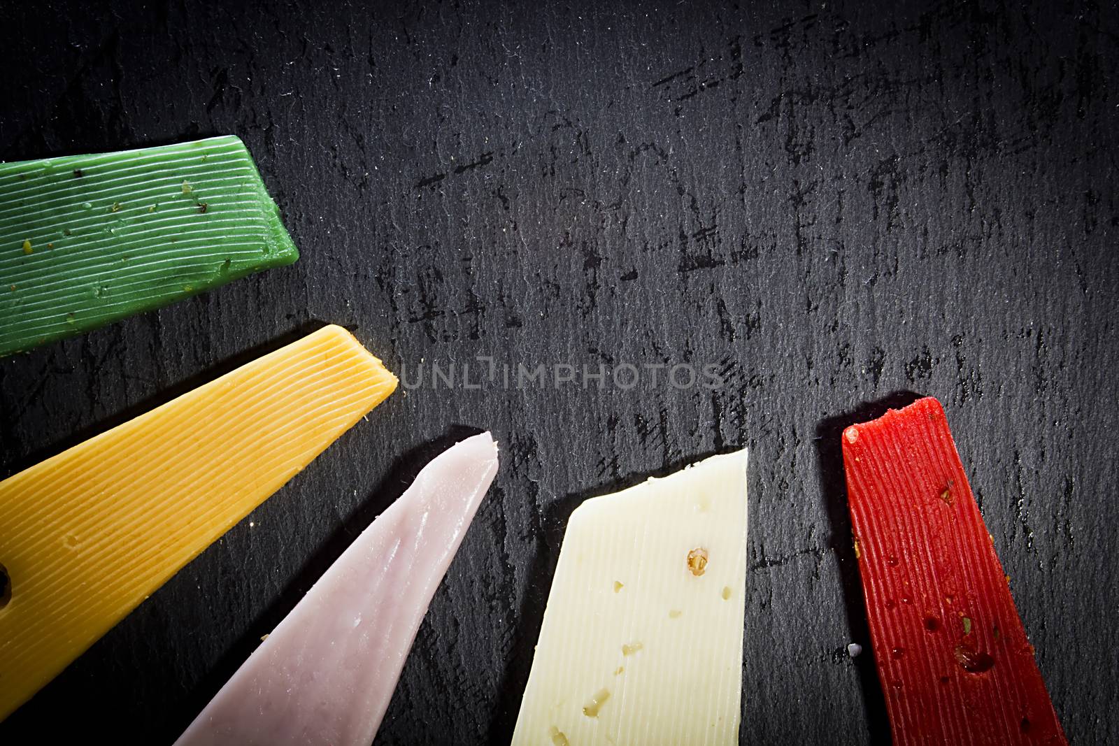 Pieces of colorful cheeses on black wooden background