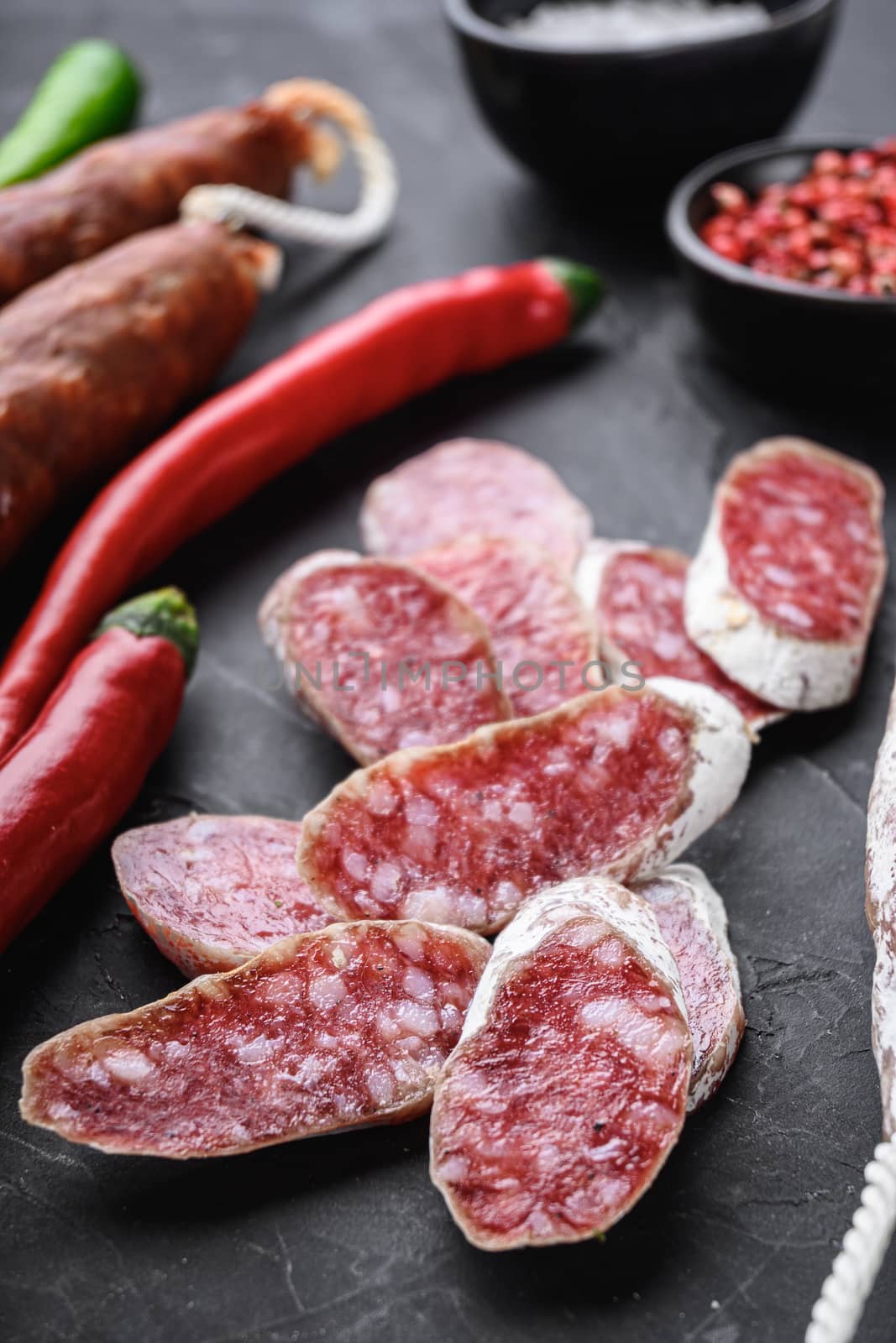Set of various spanish dry cured salami sausages slices and whole cuts on balck background.