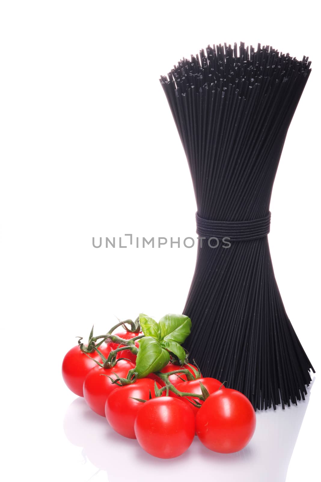 Black spaghetti with basel leaves and red tomato on white background.