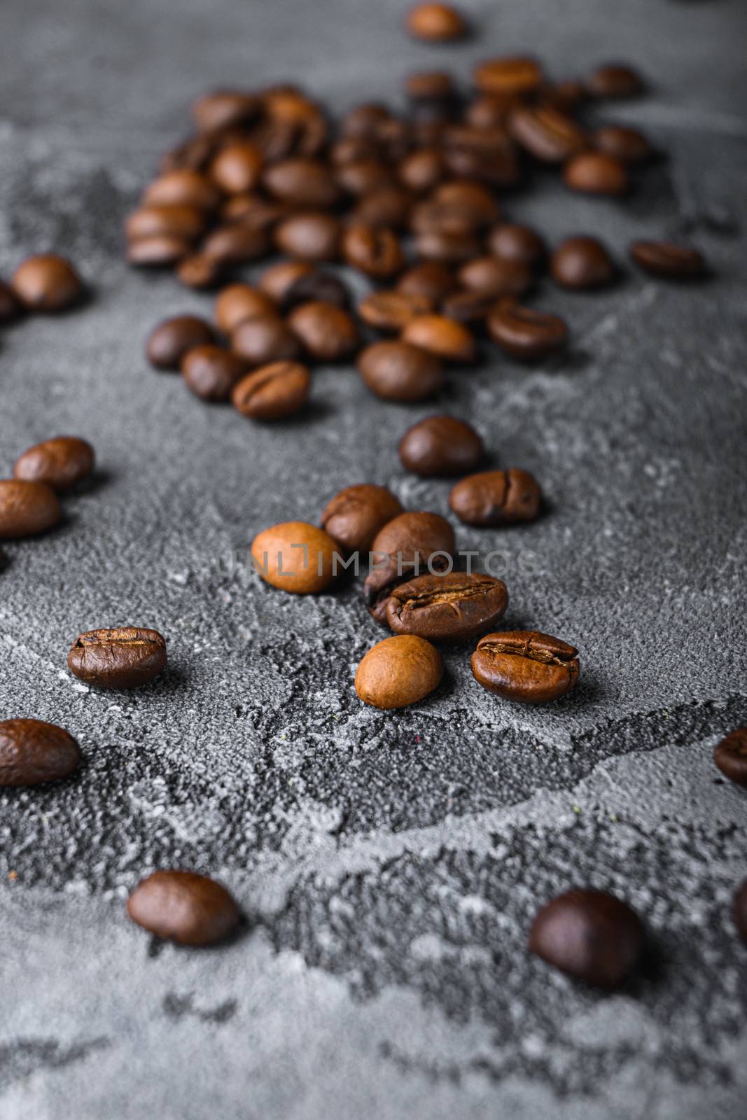 Roasted coffee beans on grey textured background.