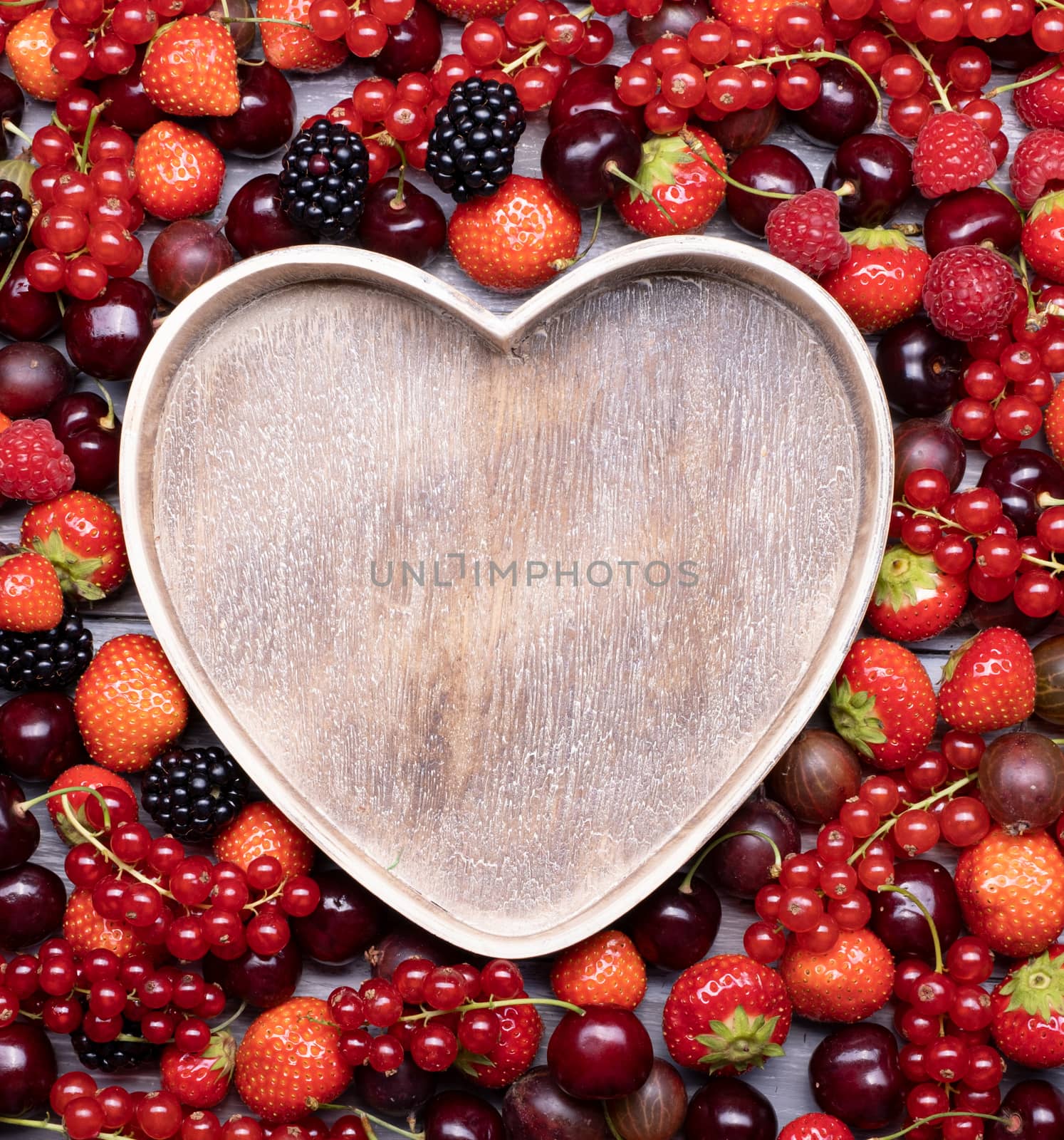 Berries upstairs closeup of colorful assorted mix as a background with a place for inscription in the form of a heart