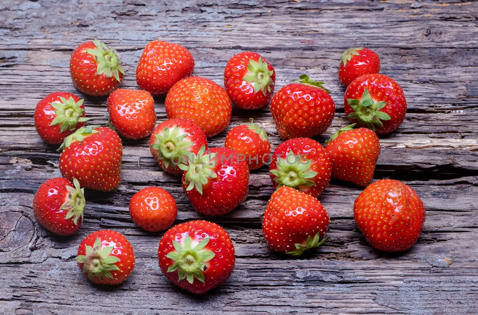 Group strawberries with strawberry leaf on old wooden background.