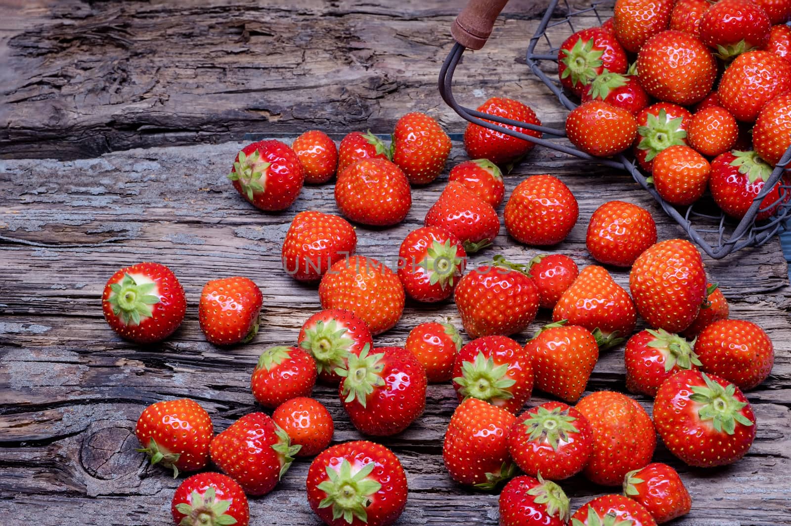 Group strawberries with strawberry leaf on old wooden background.