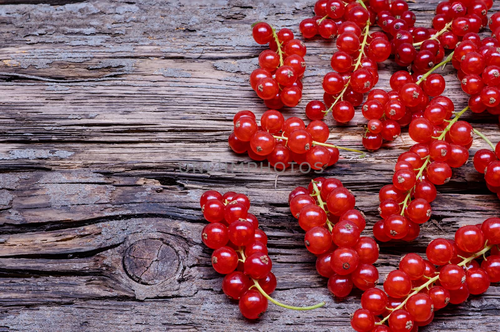 Red currant a metal basket, top view on old wooden background.