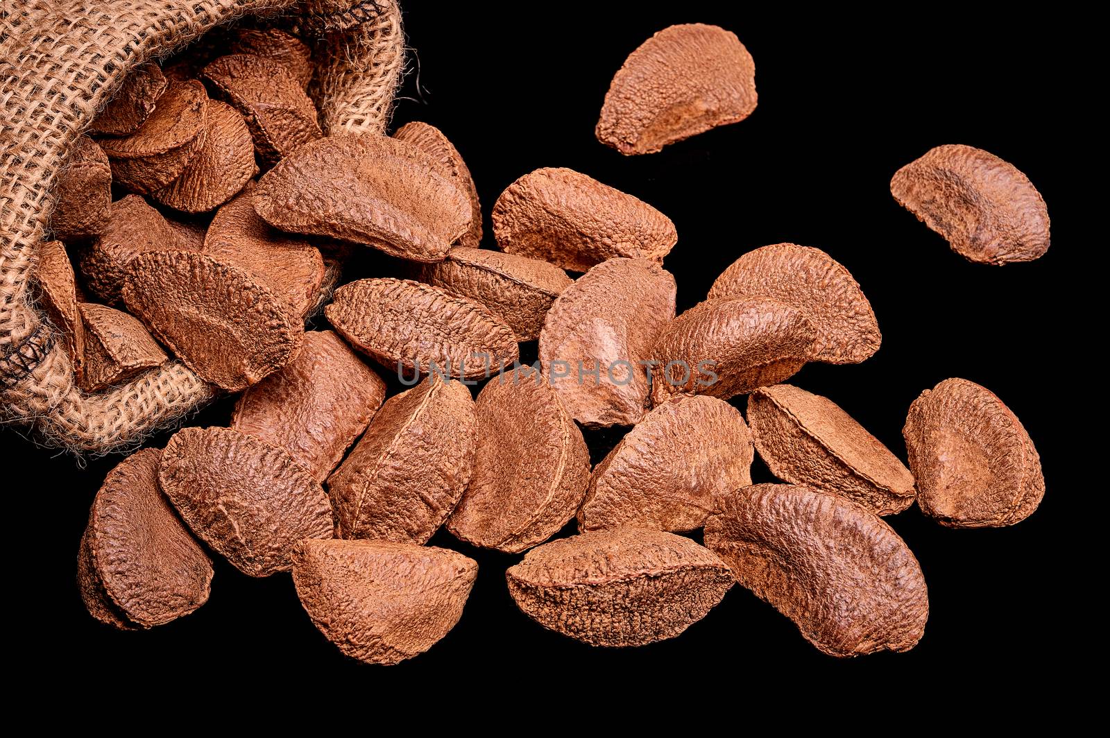 Paranuts in bag, vegetarian food in wooden bowls, on black background.