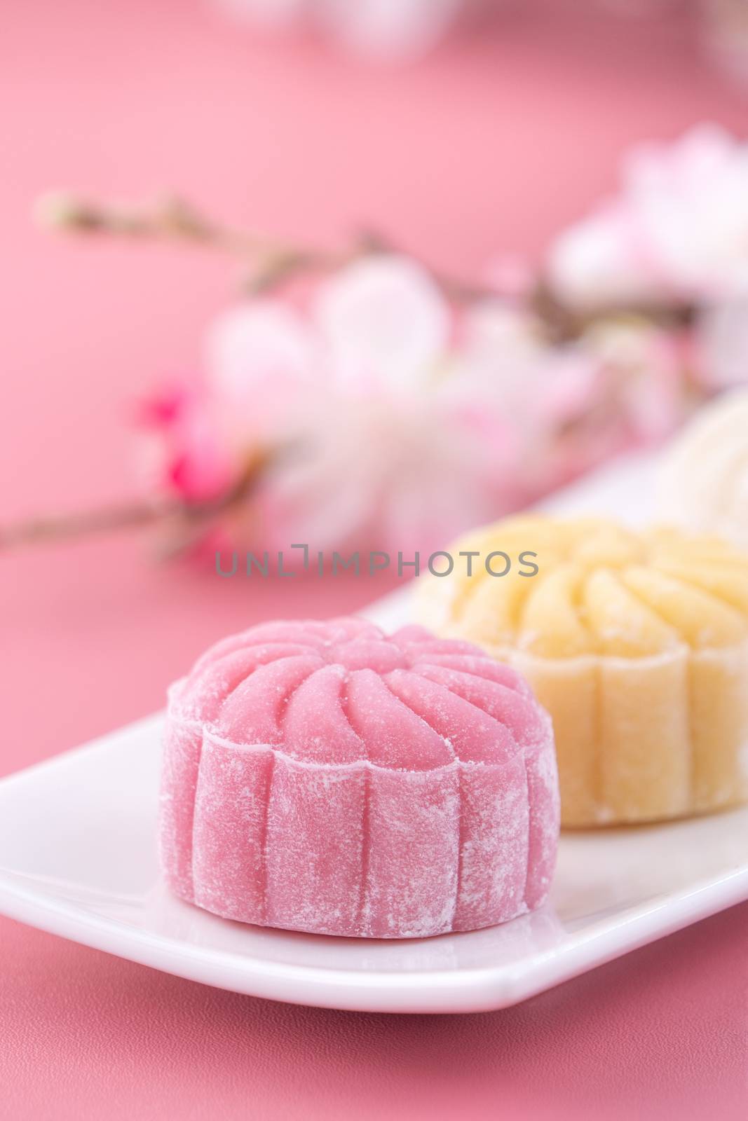 Colorful snow skin moon cake, sweet snowy mooncake, traditional savory dessert for Mid-Autumn Festival on pastel pale pink background, close up, lifestyle.