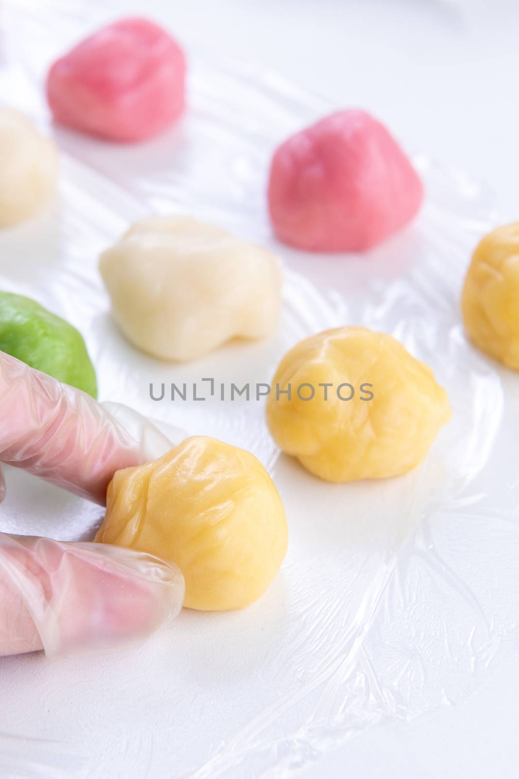 Young woman is making colorful snow skin moon cake, recipe of sweet snowy mooncake, traditional savory dessert for Mid-Autumn Festival, close up, lifestyle.