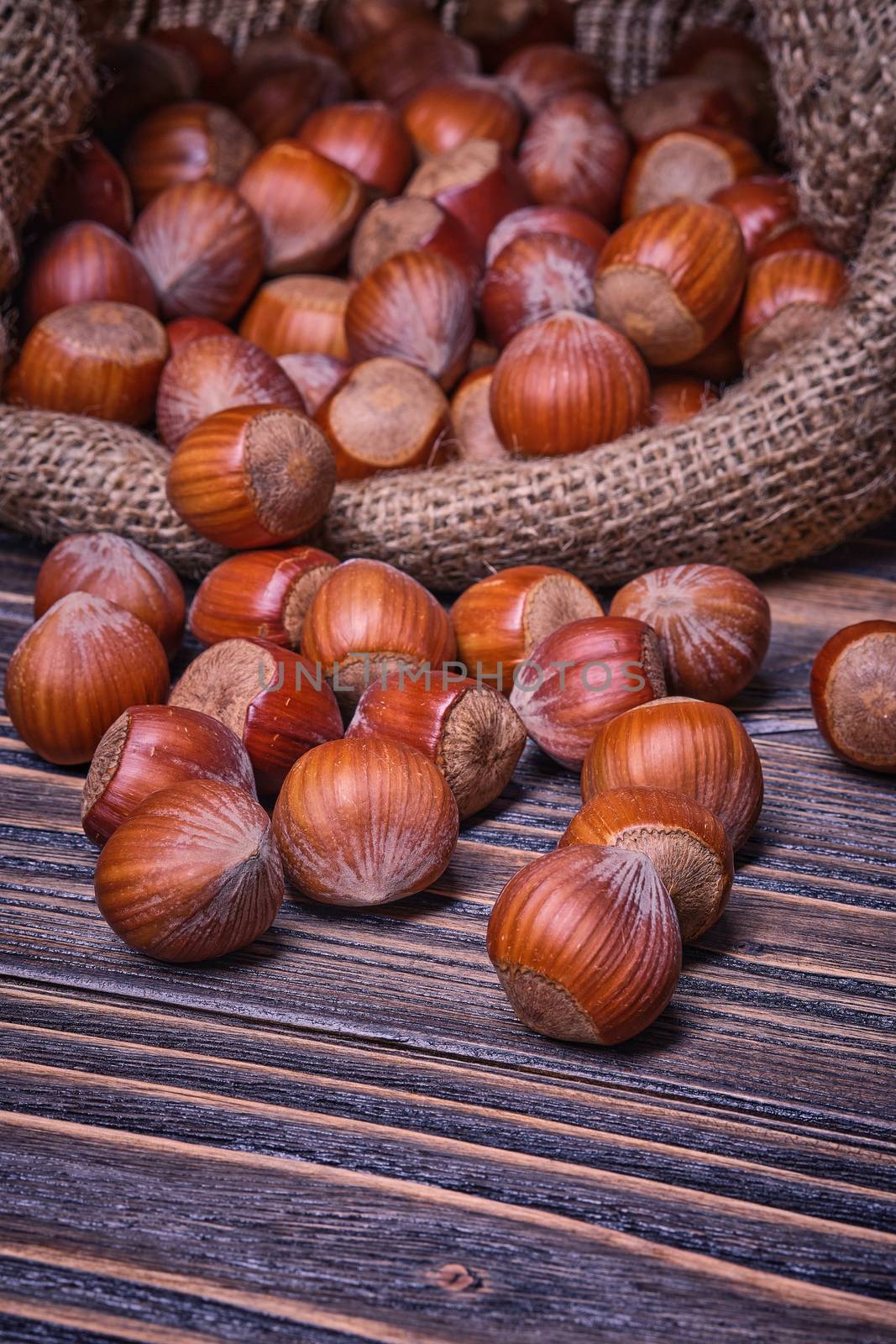 Hazelnuts in bag, vegetarian food in wooden bowls, on old wooden background by Fischeron