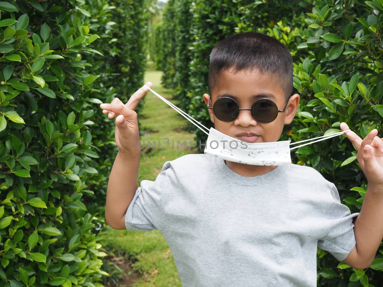 Portrait of a boy wearing black glasses And wearing a protective mask On a green background by Unimages2527