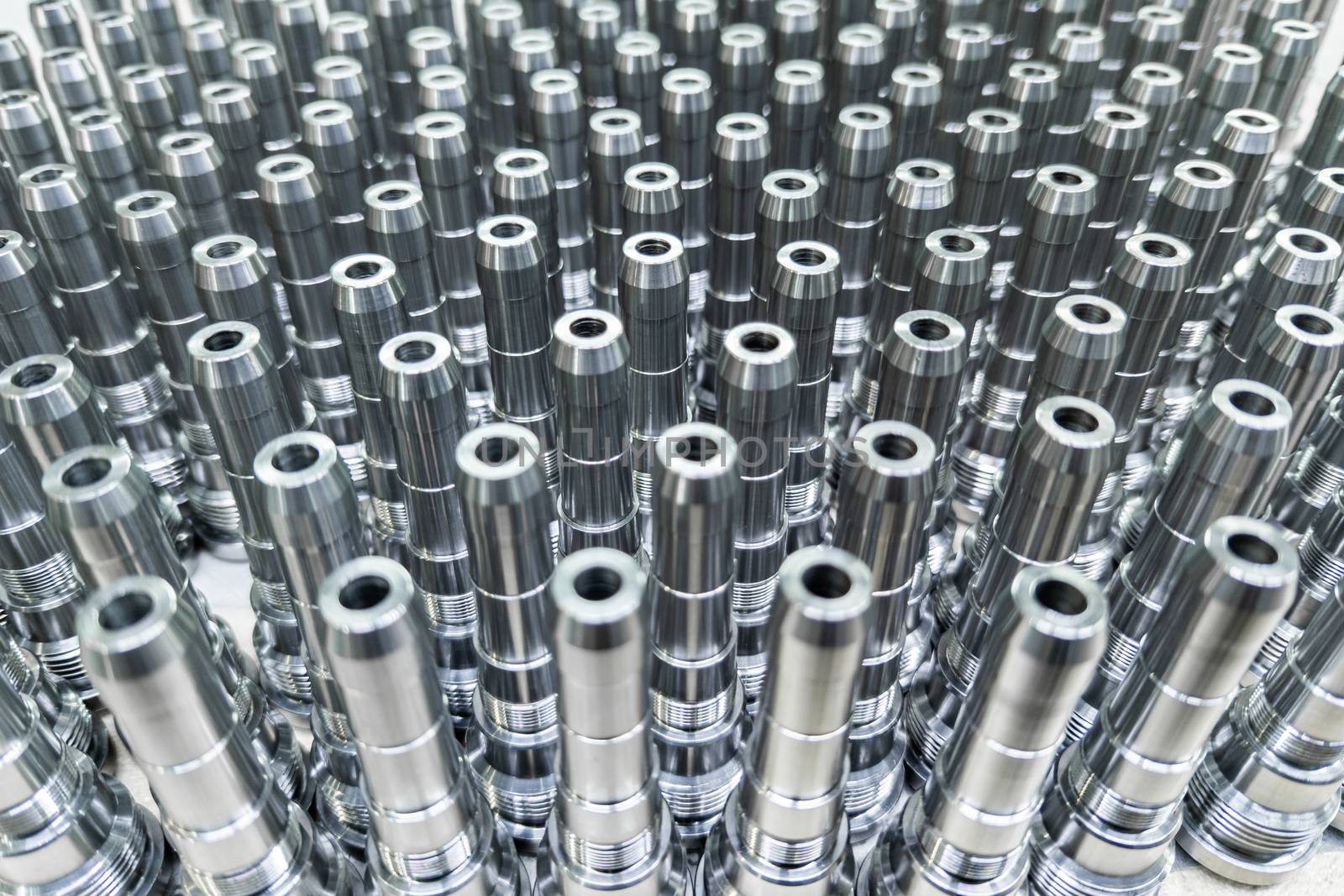 Shiny long steel parts full frame background, clean steel threaded rods after fine cnc turning standing vertically.