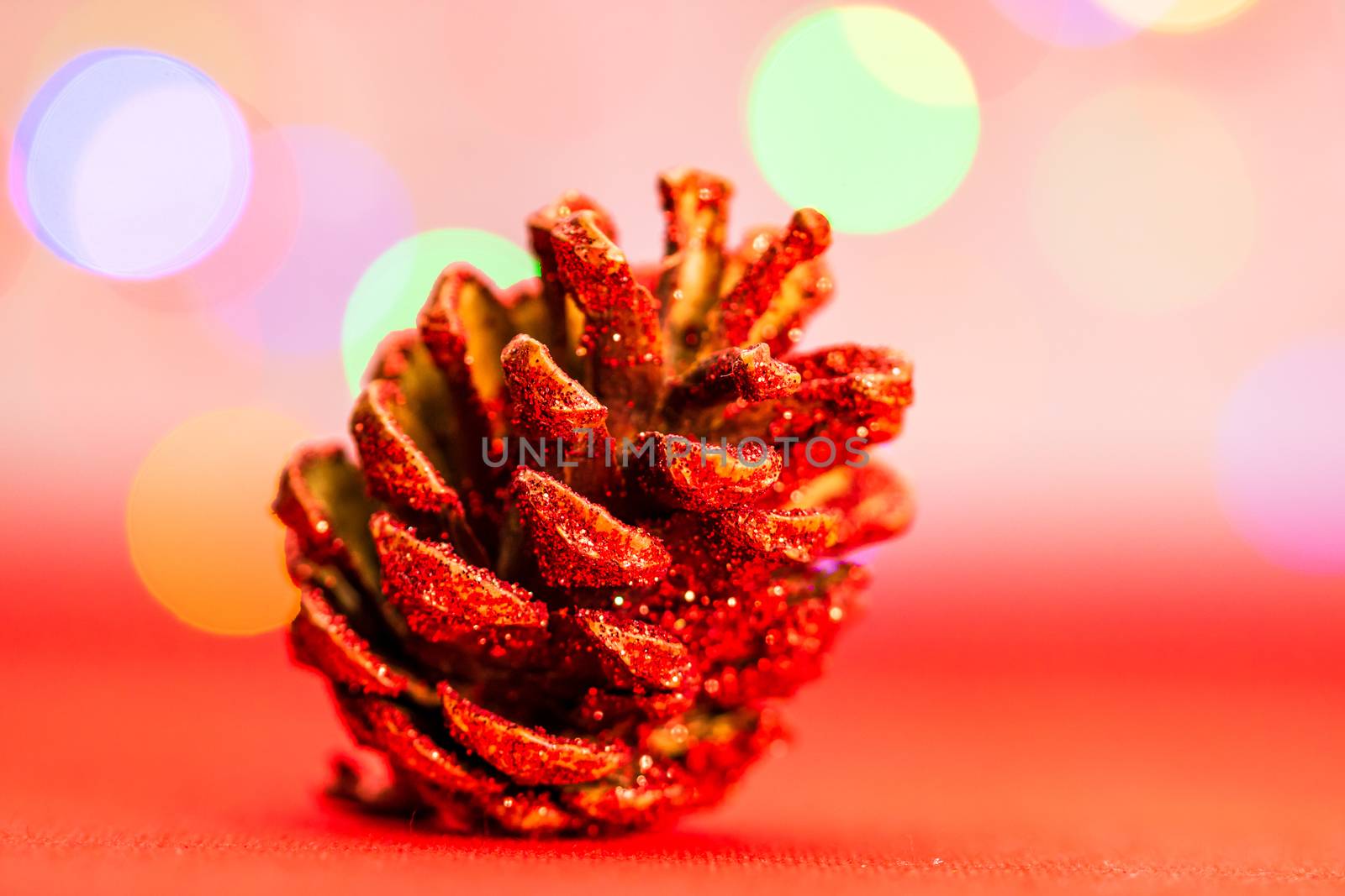 Red glittery decoration in a colorful Christmas composition isolated on background of blurred lights.