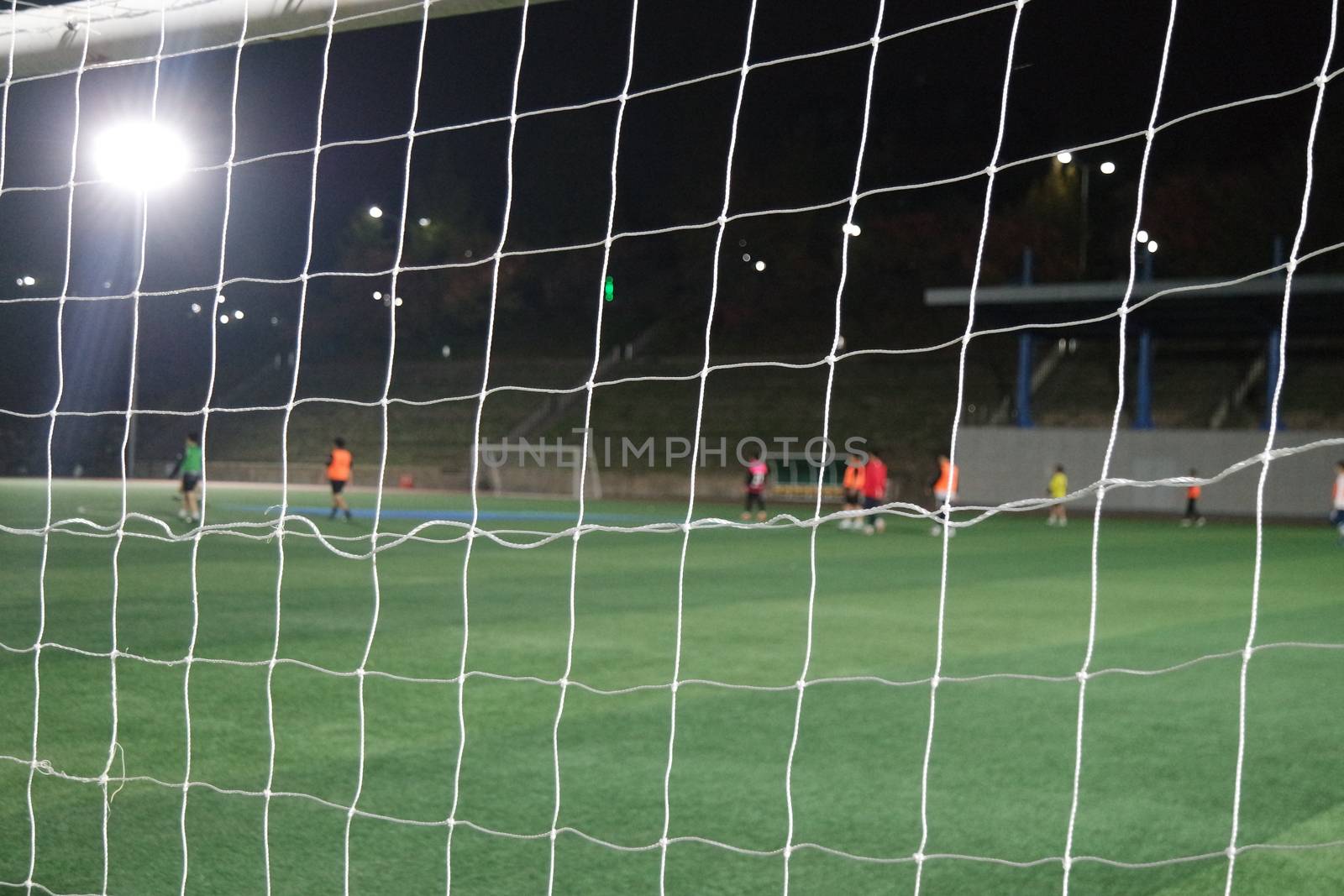 Night view of a soccer goal net under flood lights. Closeup view of goal net in a soccer playground