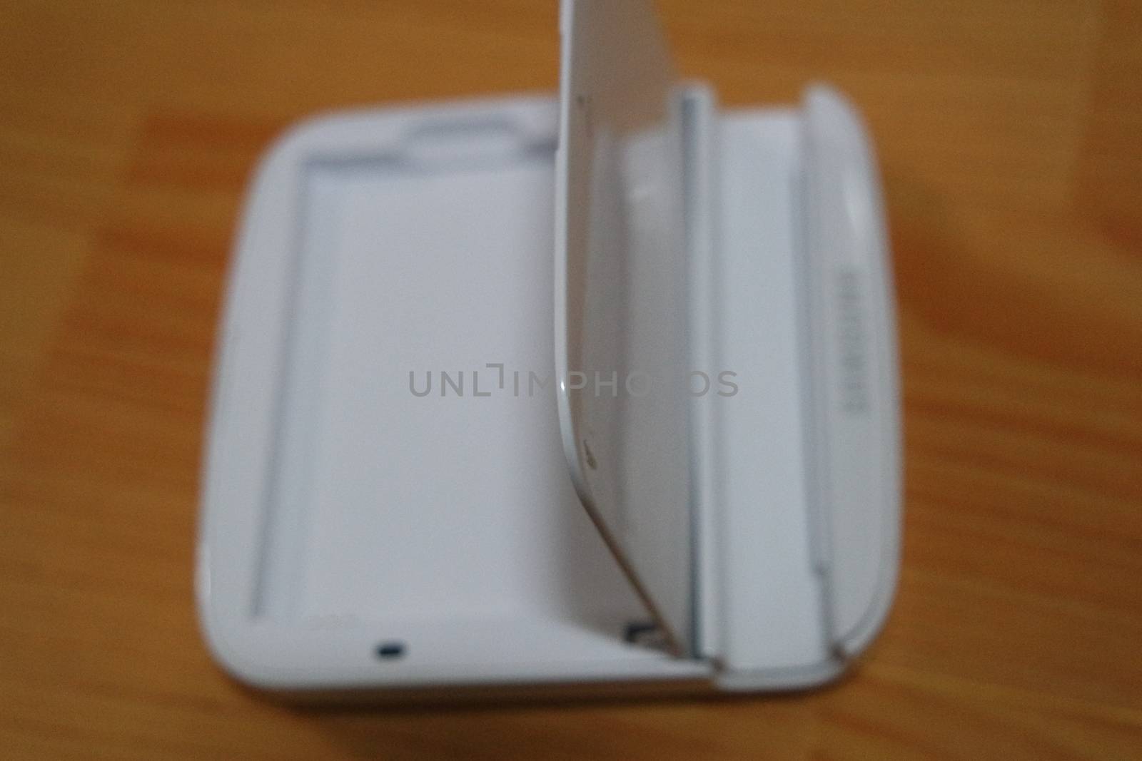 White colored battery charging box for electronic devices like mobile phone. Potable charging box is placed on a wooden floor.