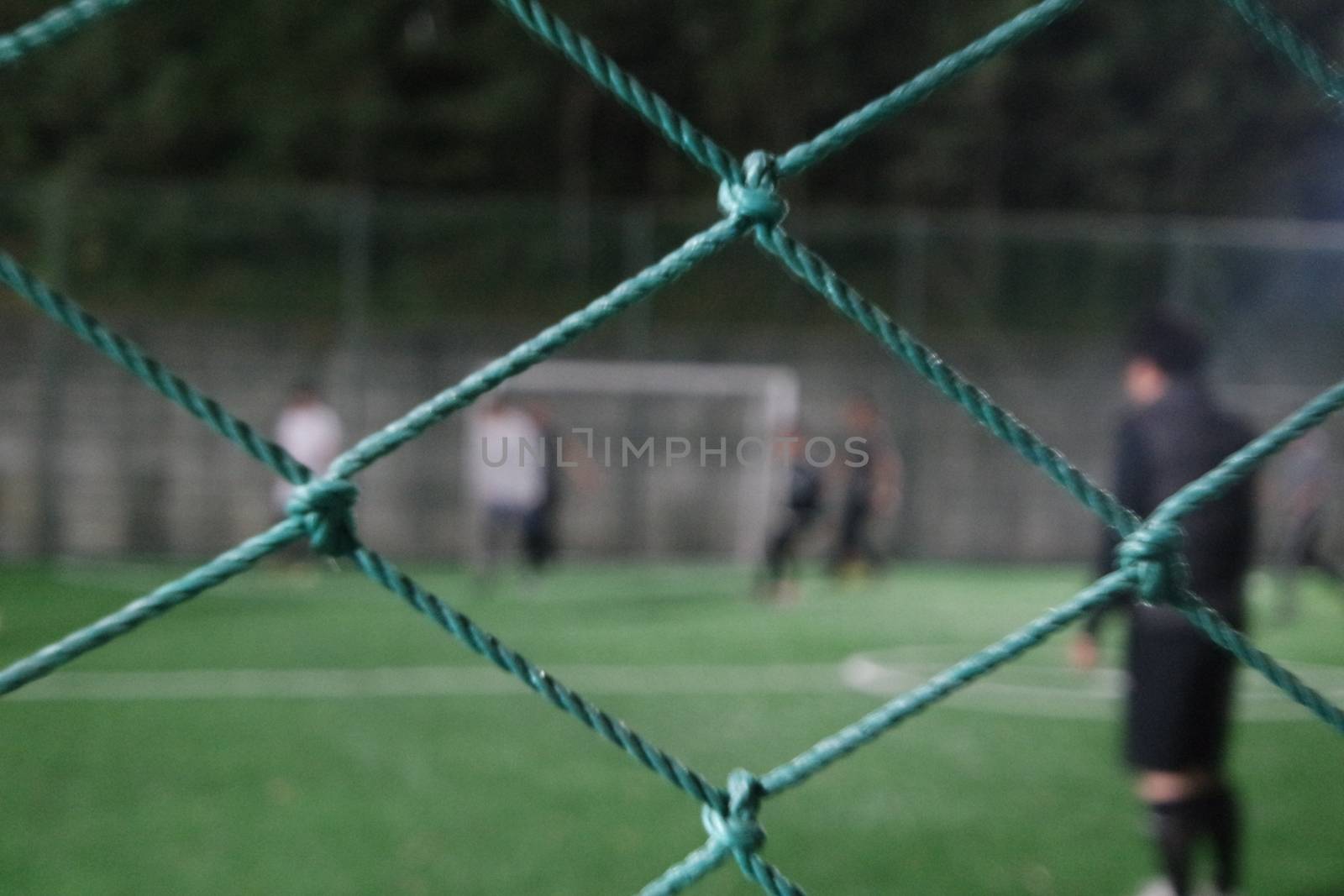 Night view of a soccer goal net under flood lights. Closeup view of goal net in a soccer playground