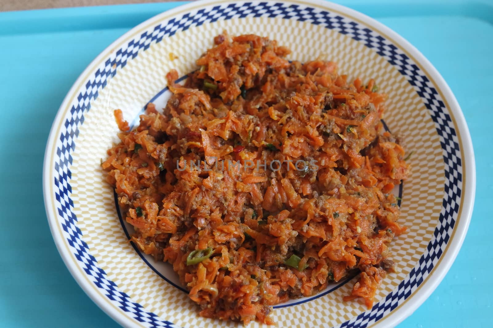 Top closeup view of a homemade dish made from carrot and vegetables served in a ceramic plate.