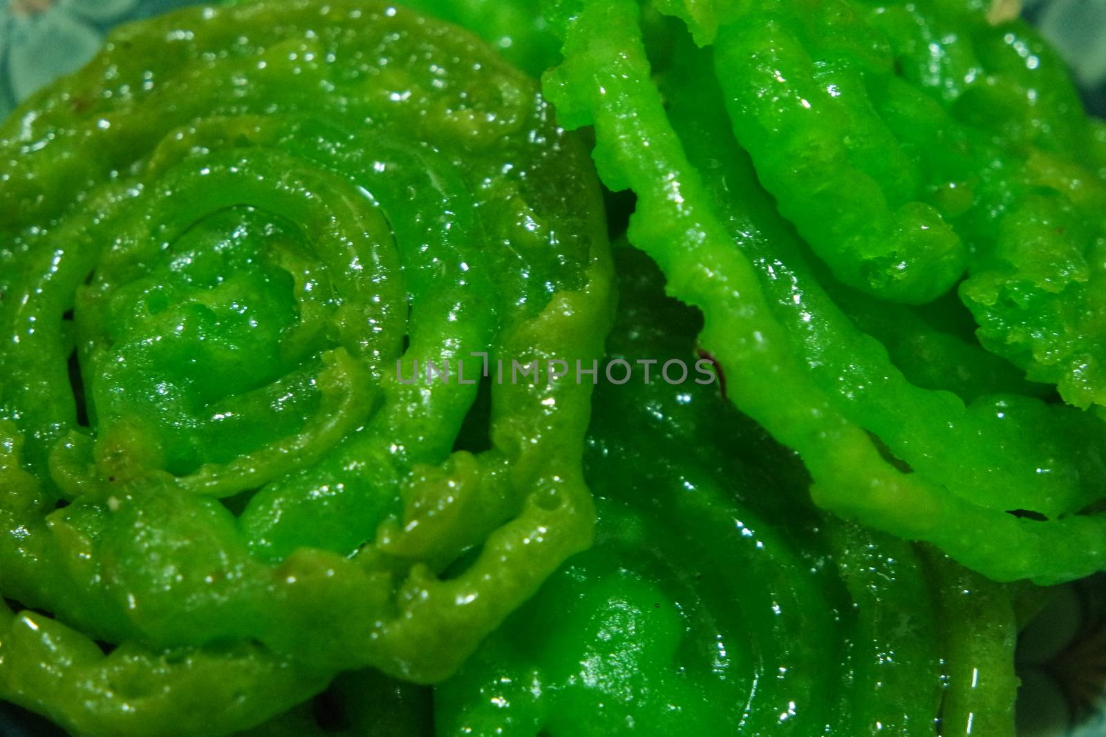 Crispy sweet Asian dessert green Jalebi cooked and served in Festival, Indian sweet street food with juicy syrup, a closeup view.