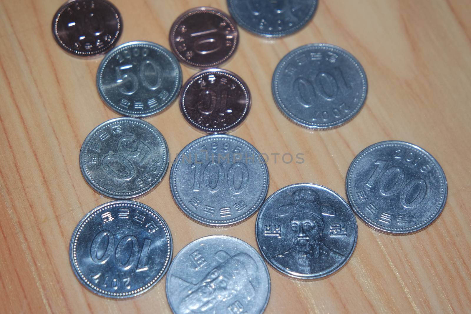 Silver shining Korean won coin scattered over a wooden floor.