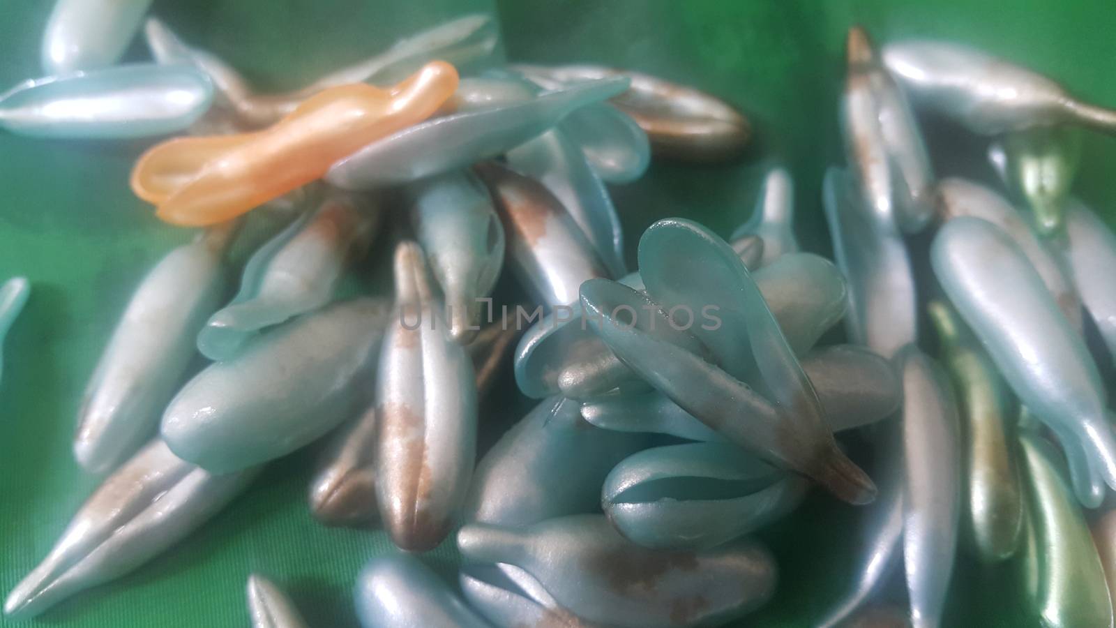 Colorful shiny bright oil capsule spread over a green background. Olden opaque oil capsules.