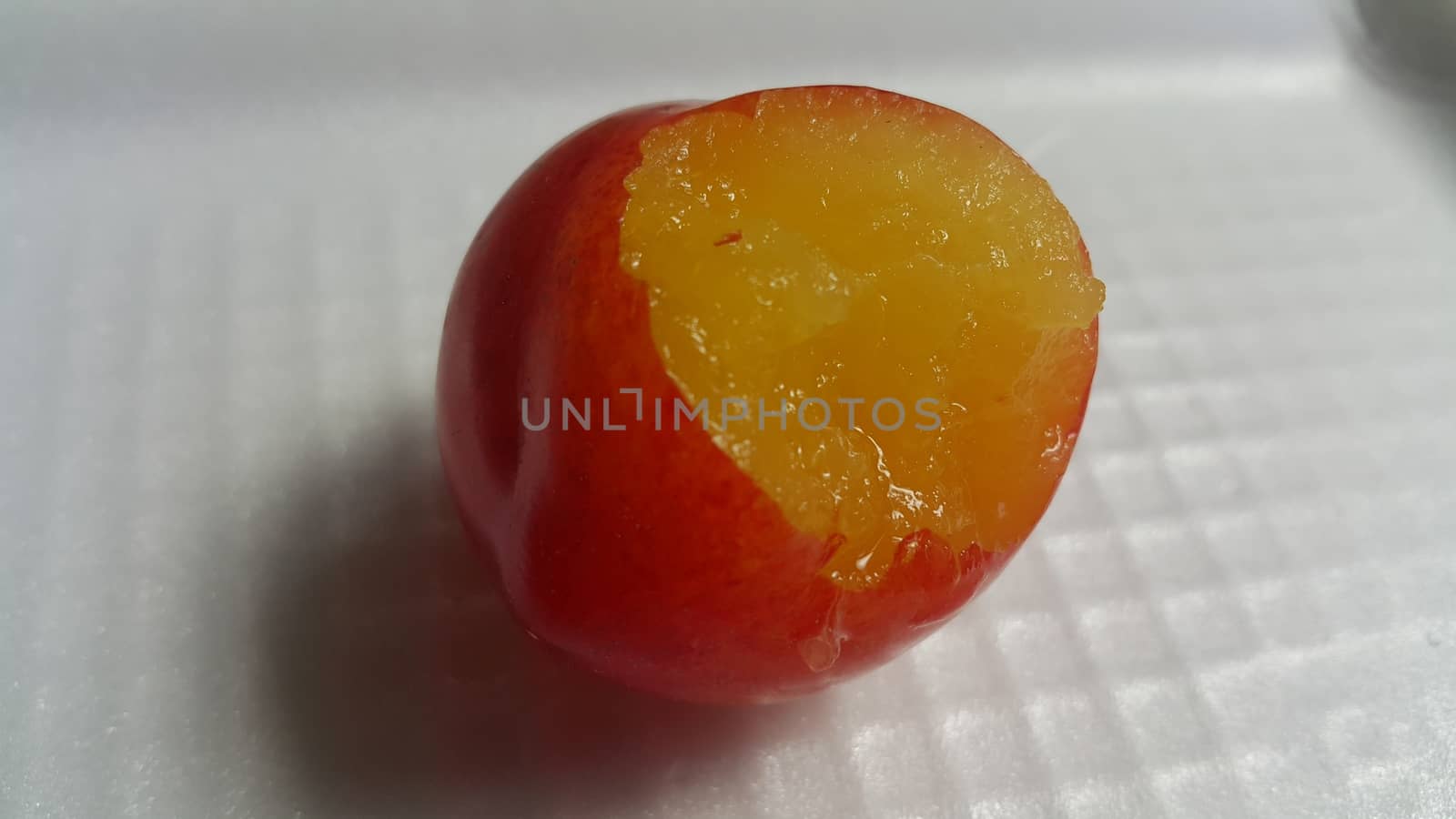 Closeup view of red plum on a white grey background. Freshly harvested plum making heart shape appearance in the view from angle.