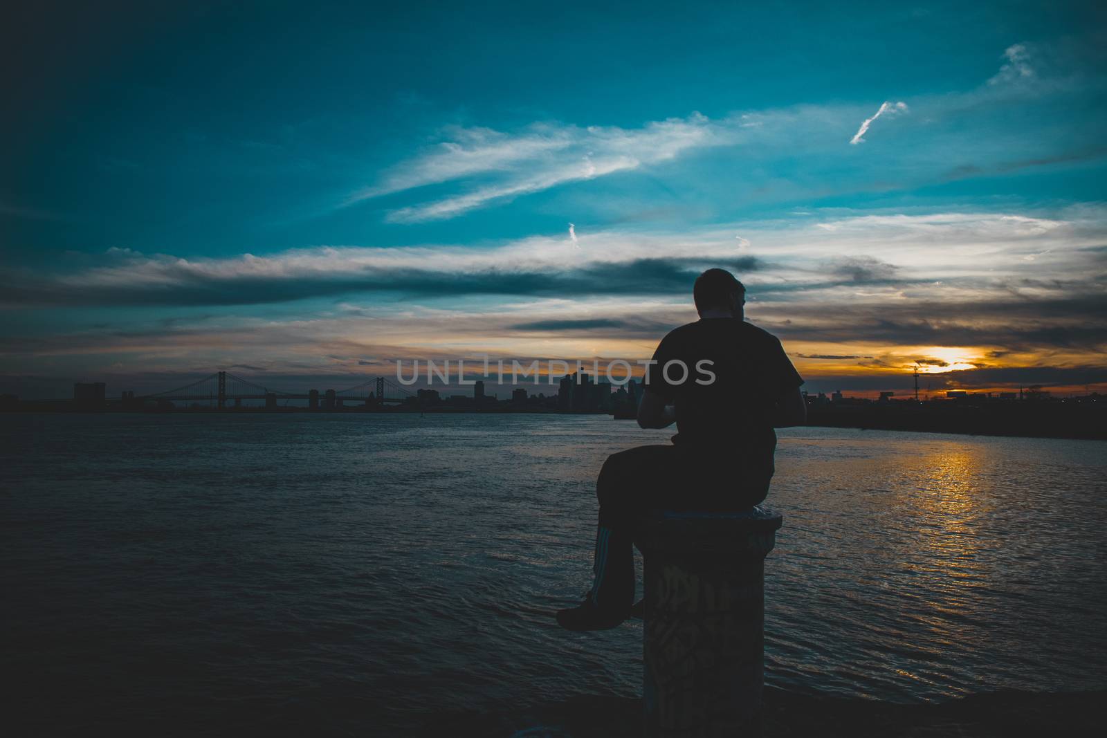 A Silhouette of a Man Sitting on a Pole at Graffiti Pier With a  by bju12290
