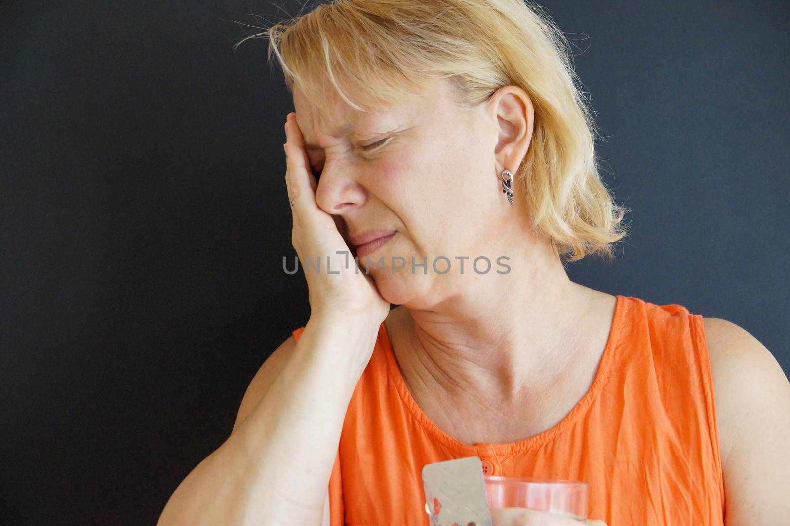 unhappy woman holding her head with her hand, portrait on black background.