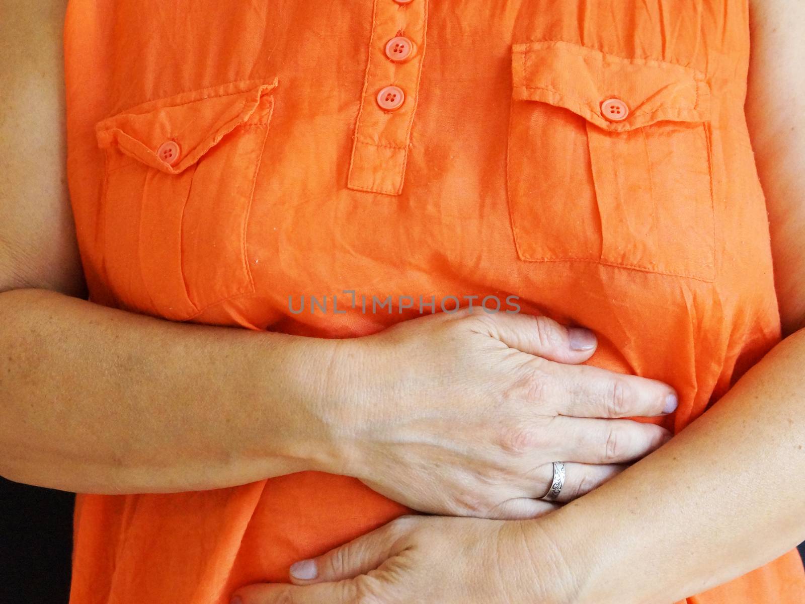 woman holding her sore belly with her hands close up by Annado