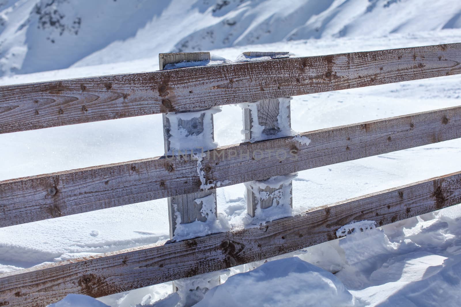 Wooden fence deep in heavy snow load on a bright sunny day.