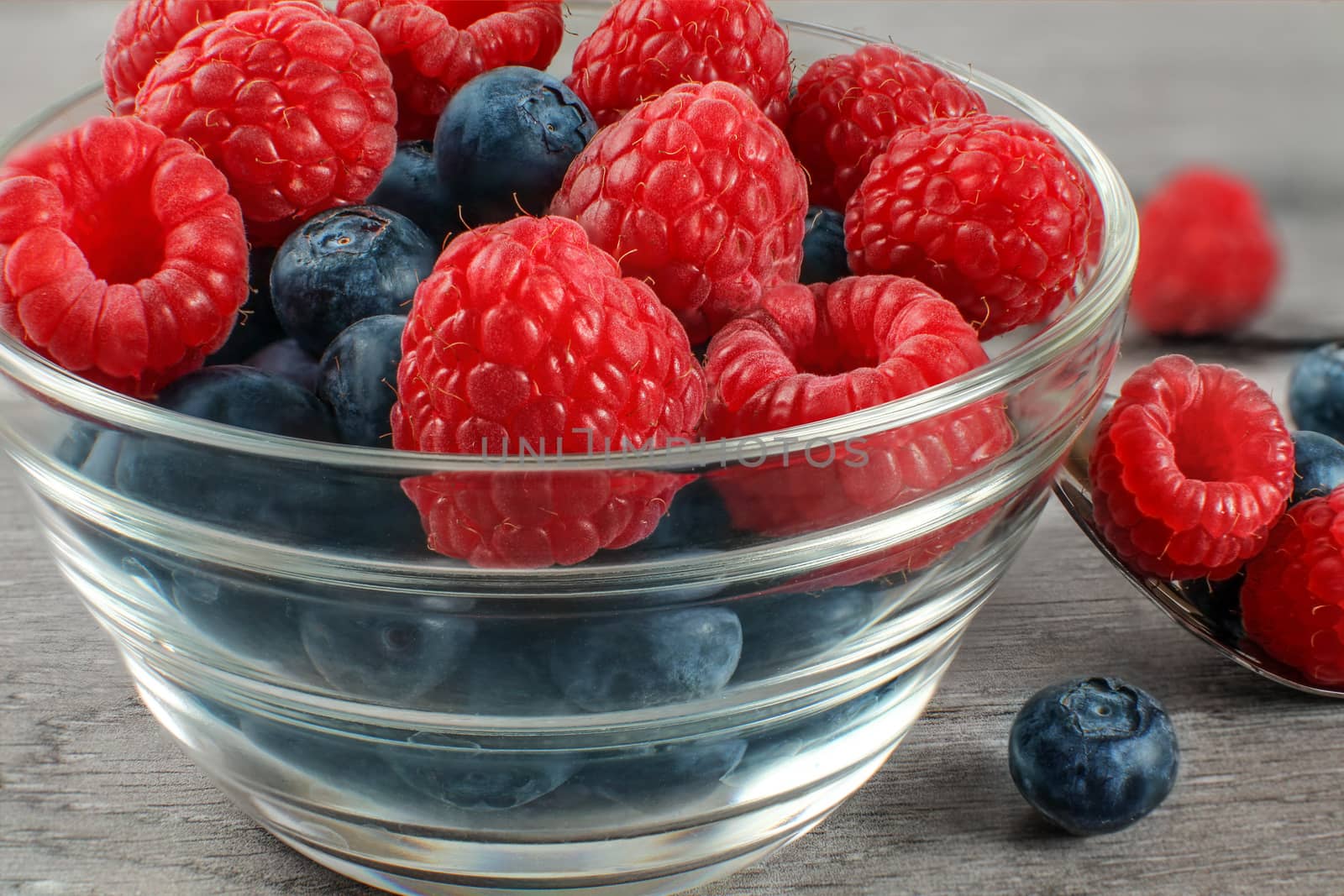 Detail on small glass bowl full of mix of blueberries and raspberries.