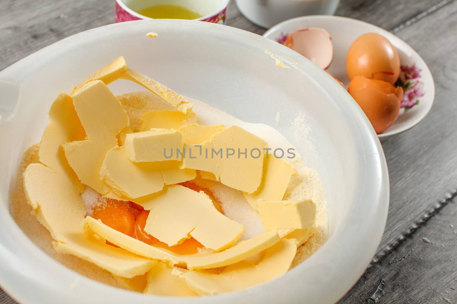 White plastic bowl with butter, egg yolks and sugar mixed - preparation for baking a cake.